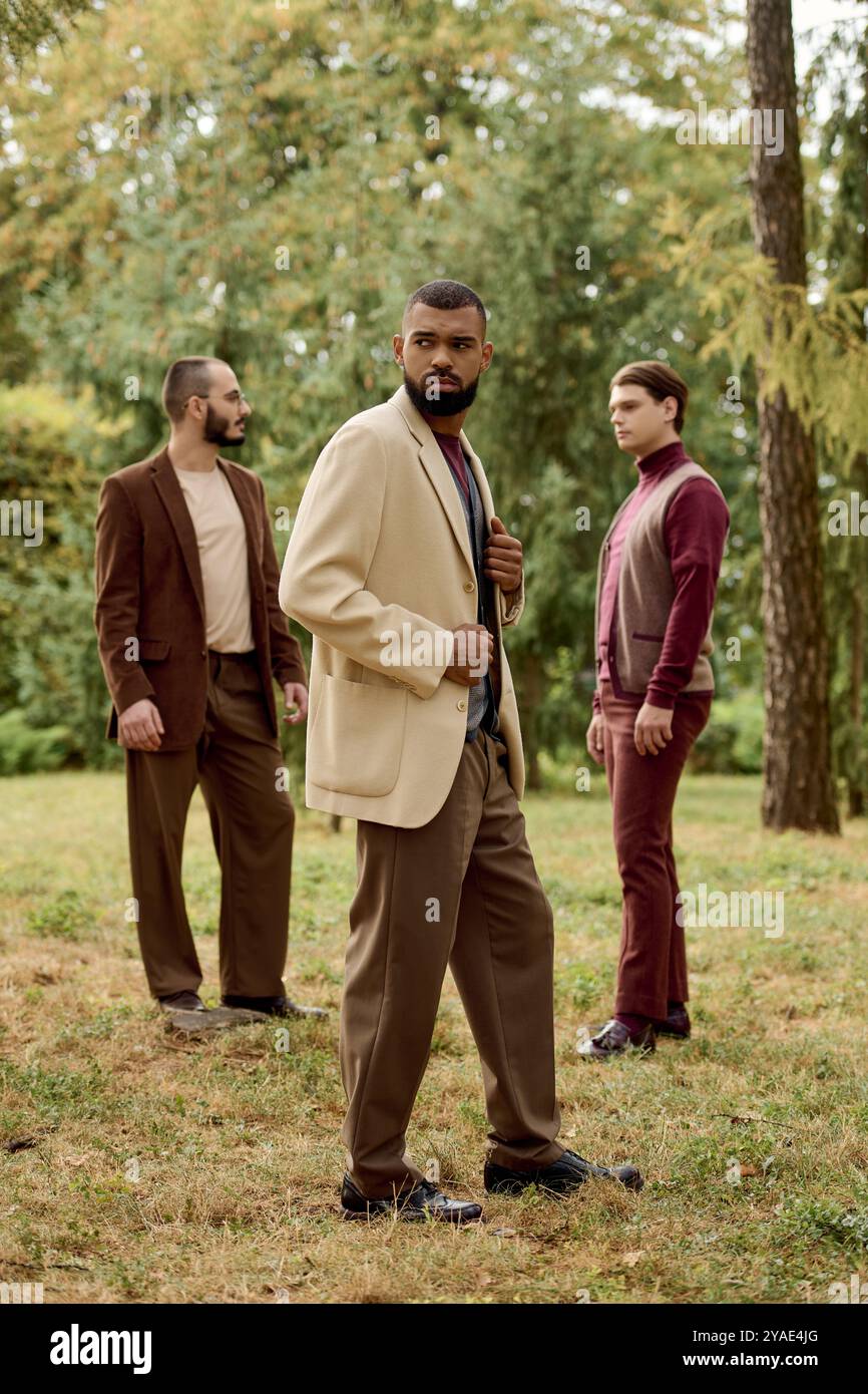 De beaux hommes mettent en valeur leur mode automnale tout en profitant d'un champ d'automne pittoresque rempli de feuillage. Banque D'Images