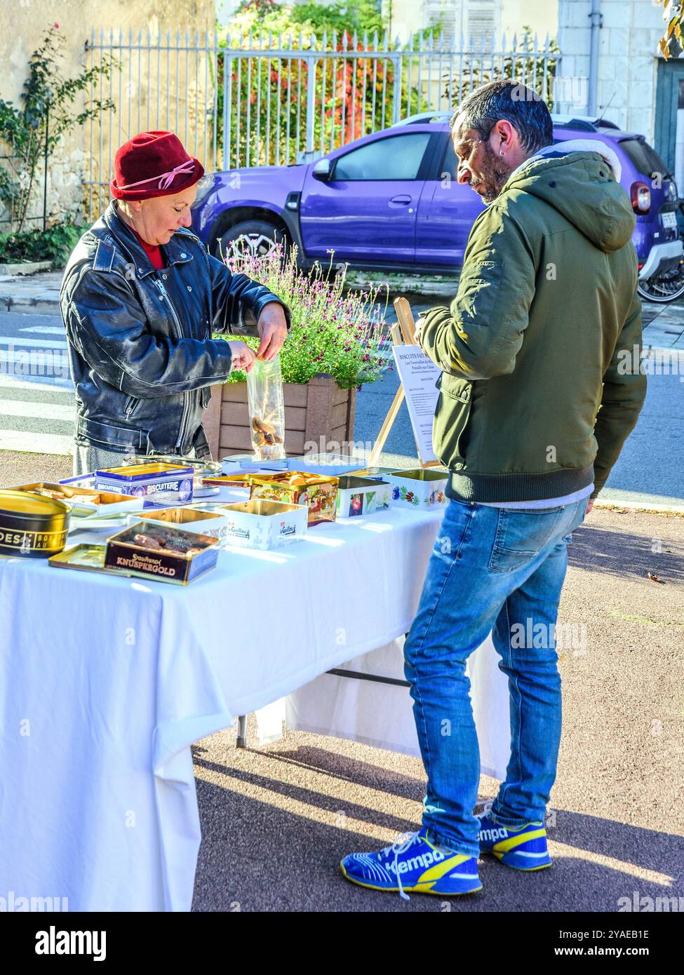 Femme avec des biscuits et des gâteaux faits maison sellin,g à un client masculin - Preuilly-sur-Claise, Indre-et-Loire (37), France. Banque D'Images