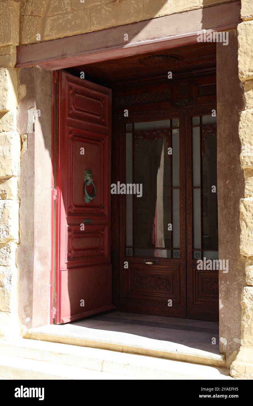 rote Tür. porte rouge. Eingang. entrée. Türklopfer. heurtoir de porte. Glastür. Kalkstein. calcaire. historisch. historique. ancien. été. Mdina. Malte. Banque D'Images