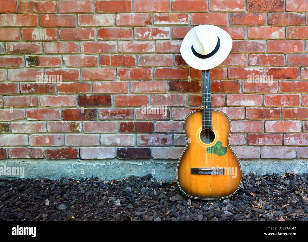 Guitar Player prend une pause laissant vieille guitare acoustique, Blues Harp et Panama Hat appuyé contre un mur de briques. Banque D'Images