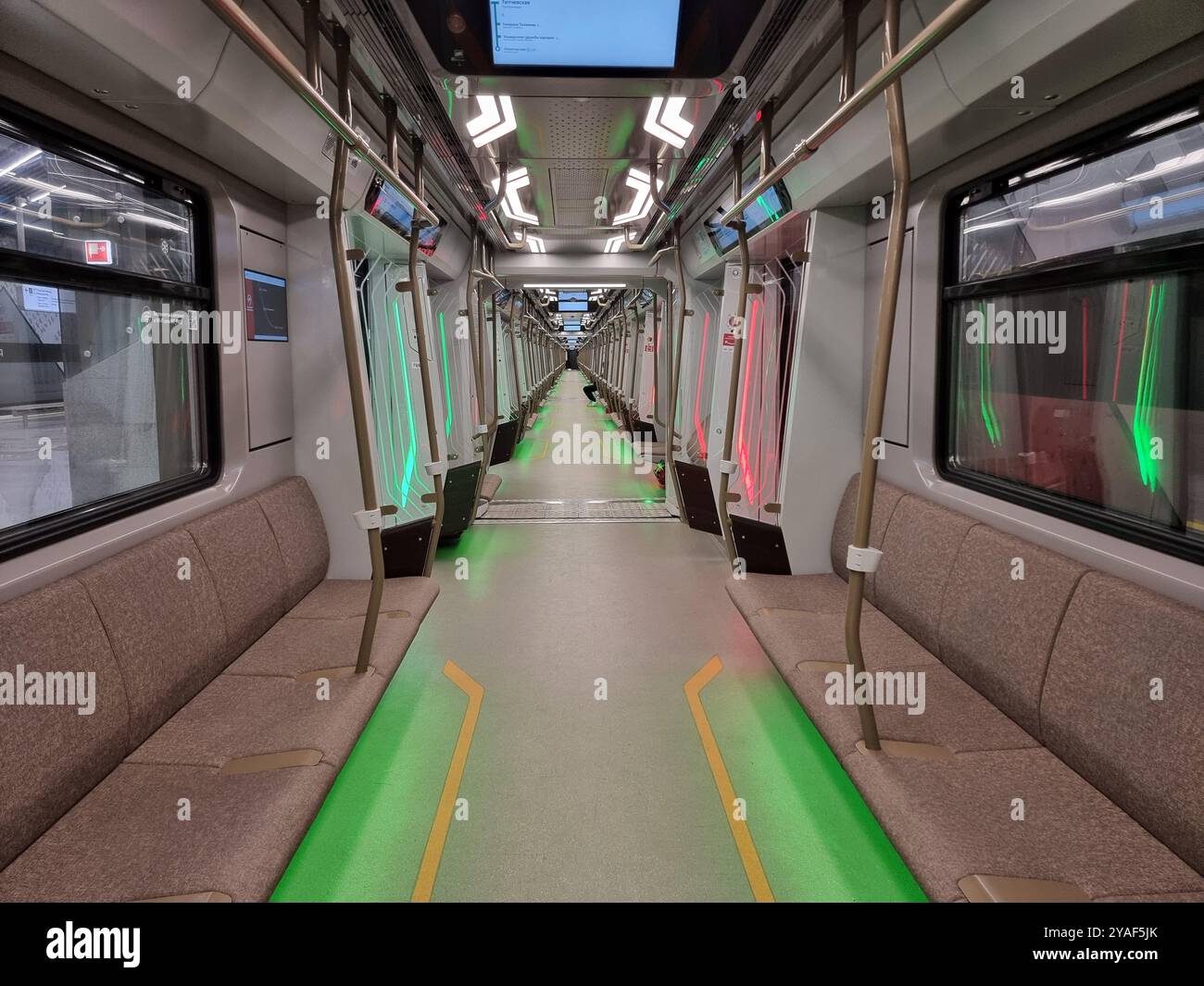 Vue de l'intérieur symétrique d'un train de métro moderne, long (presque) vide (Moskva-2024), avec éclairage au sol vert Banque D'Images