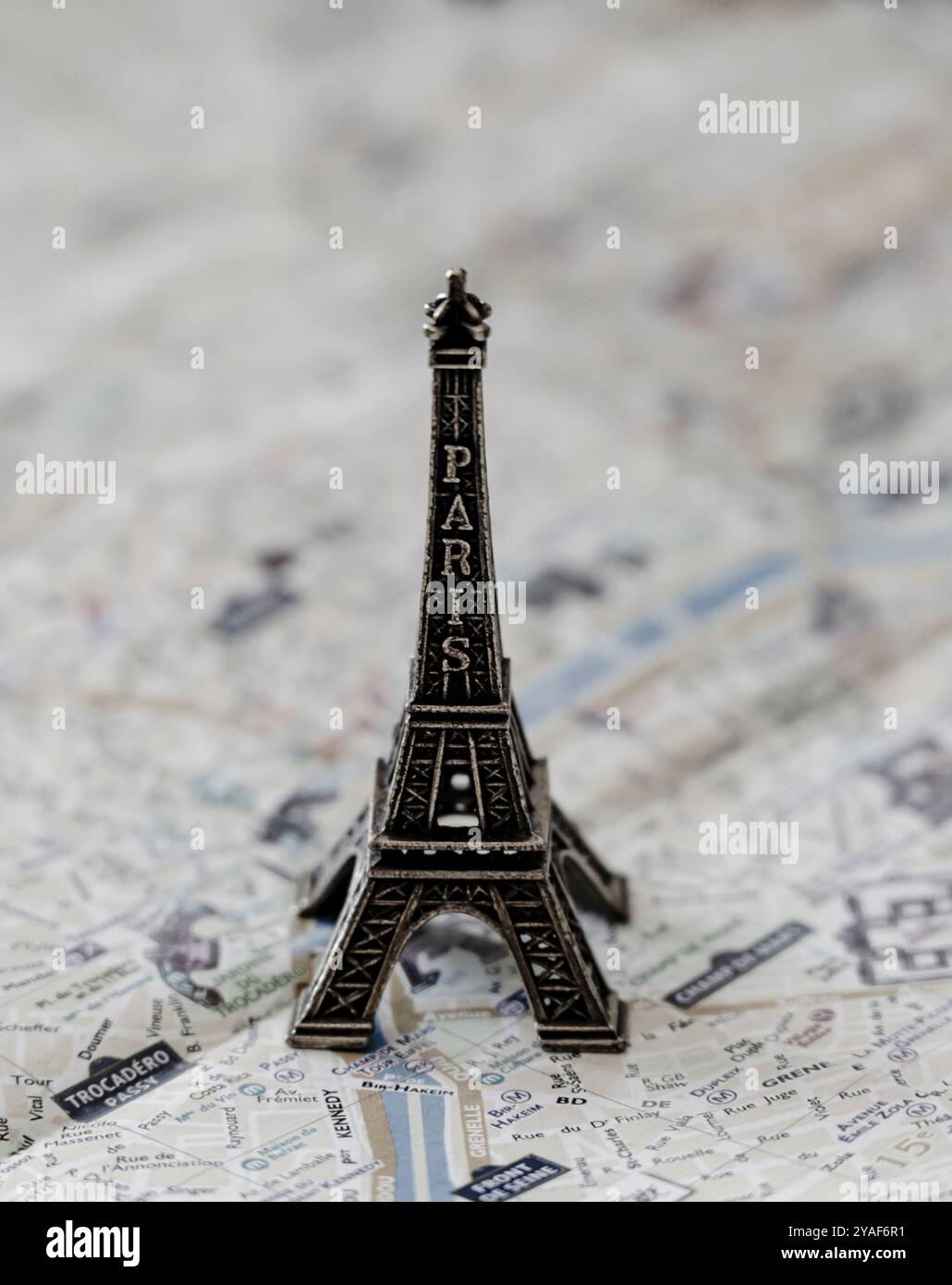 Une réplique miniature en métal de la Tour Eiffel se dresse sur un plan de rue de Paris en papier pour illustration et divertissement en noir et blanc Banque D'Images