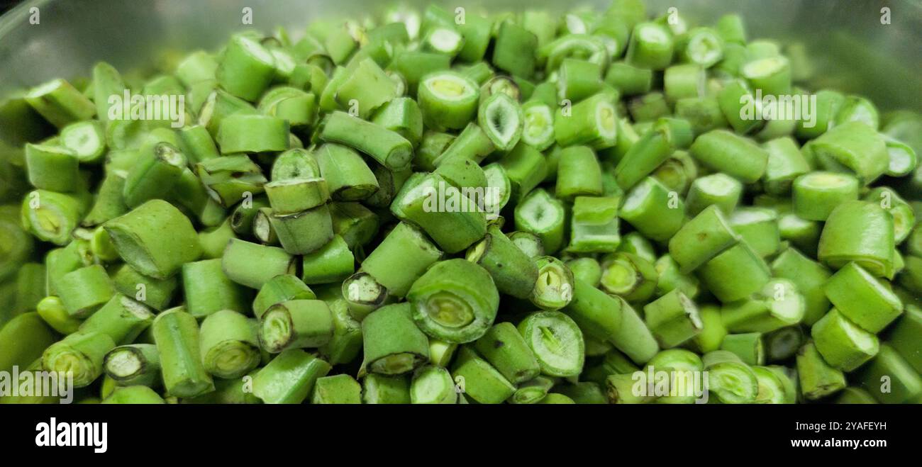 Gousses de fèves hachées prêtes à cuire. Disposé dans un bol en aluminium Banque D'Images