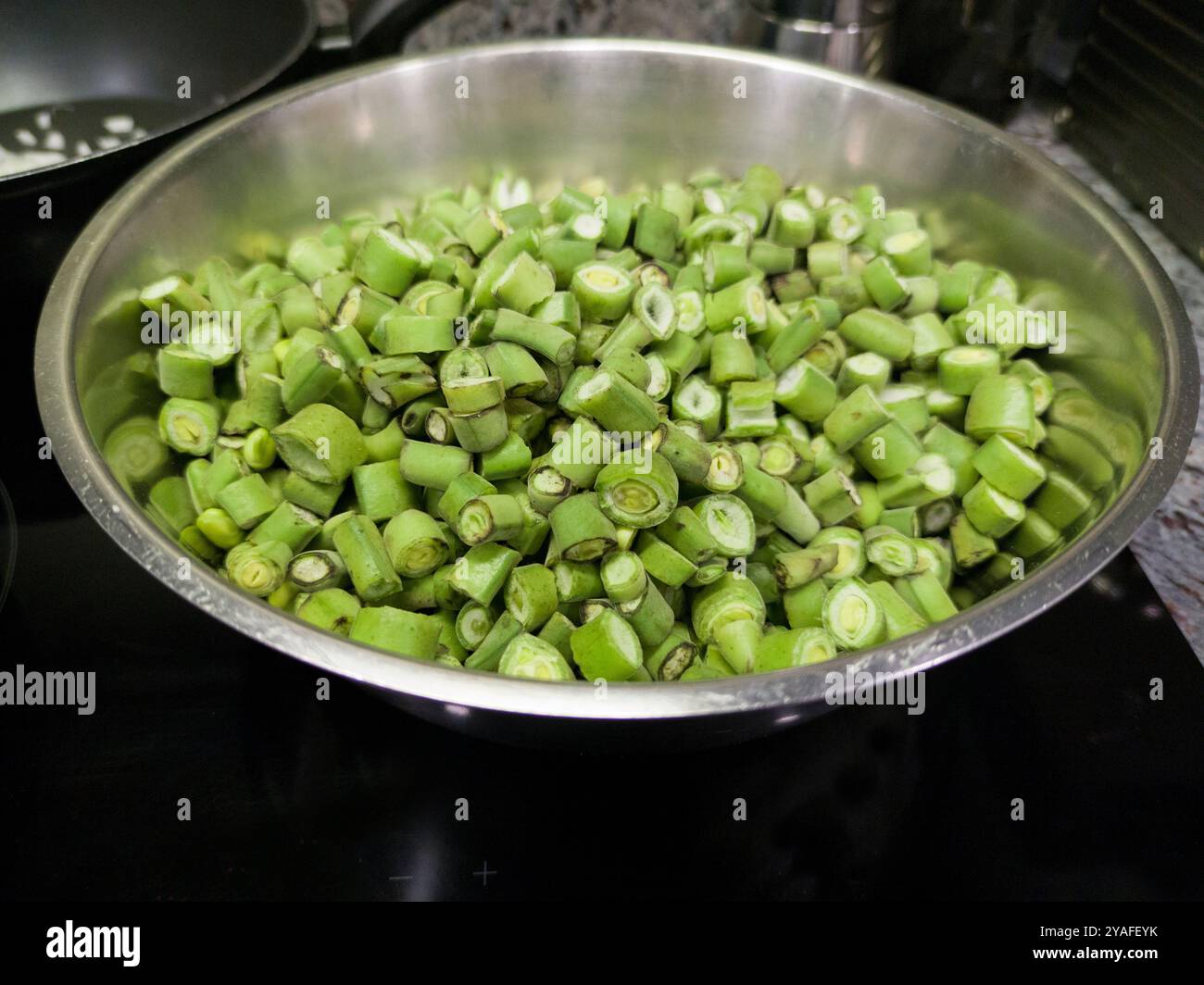 Gousses de fèves hachées prêtes à cuire. Disposé dans un bol en aluminium Banque D'Images