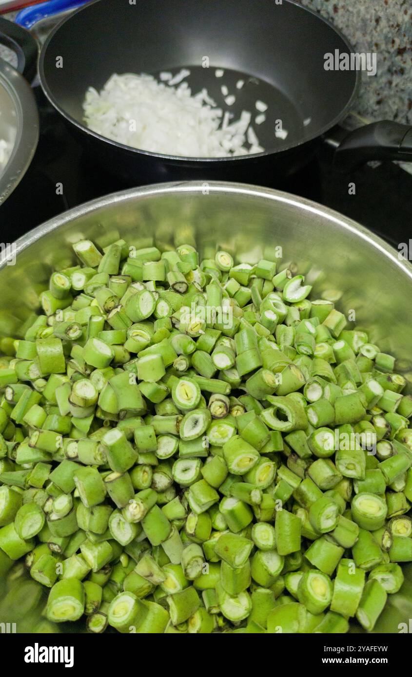 Gousses de fèves hachées prêtes à cuire. Disposé dans un bol en aluminium Banque D'Images