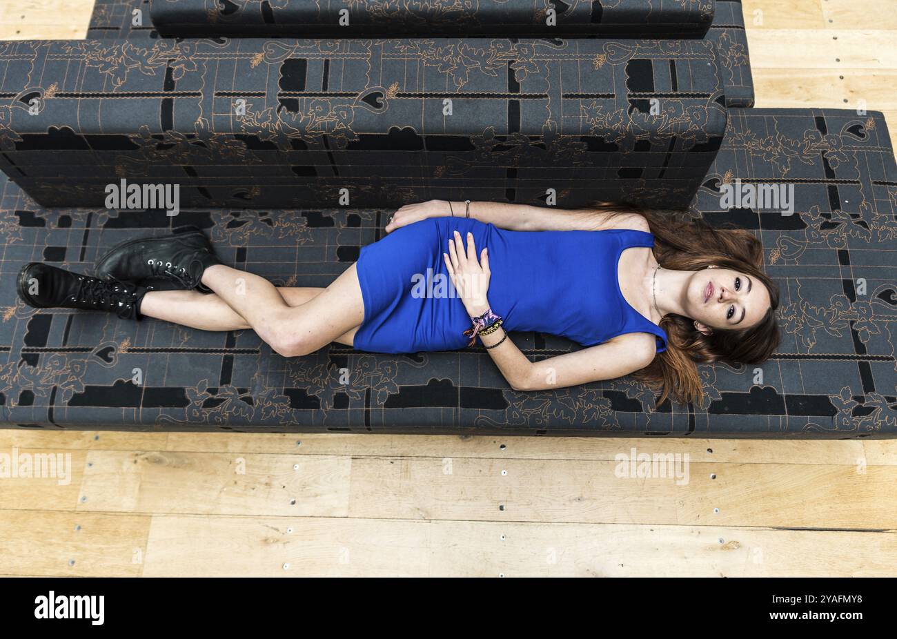 Portrait d'une femme blanche de 18 ans, vêtue d'une robe courte bleue, couchée sur un canapé gris, vue d'en haut, Bruxelles Banque D'Images
