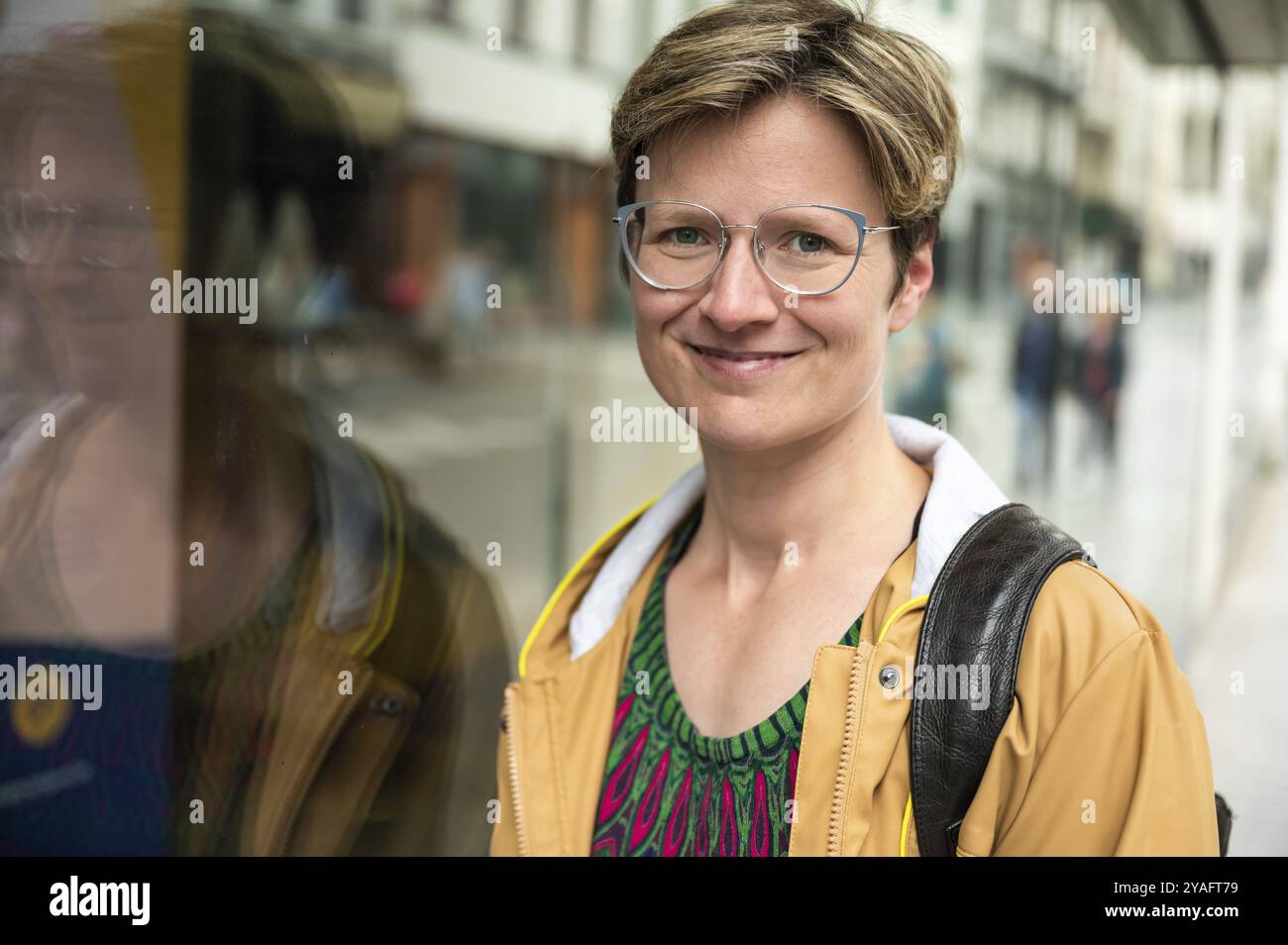 Portrait de rue réfléchi d'une femme blanche de 35 ans portant un manteau jaune, Bruxelles, Belgique, Europe Banque D'Images