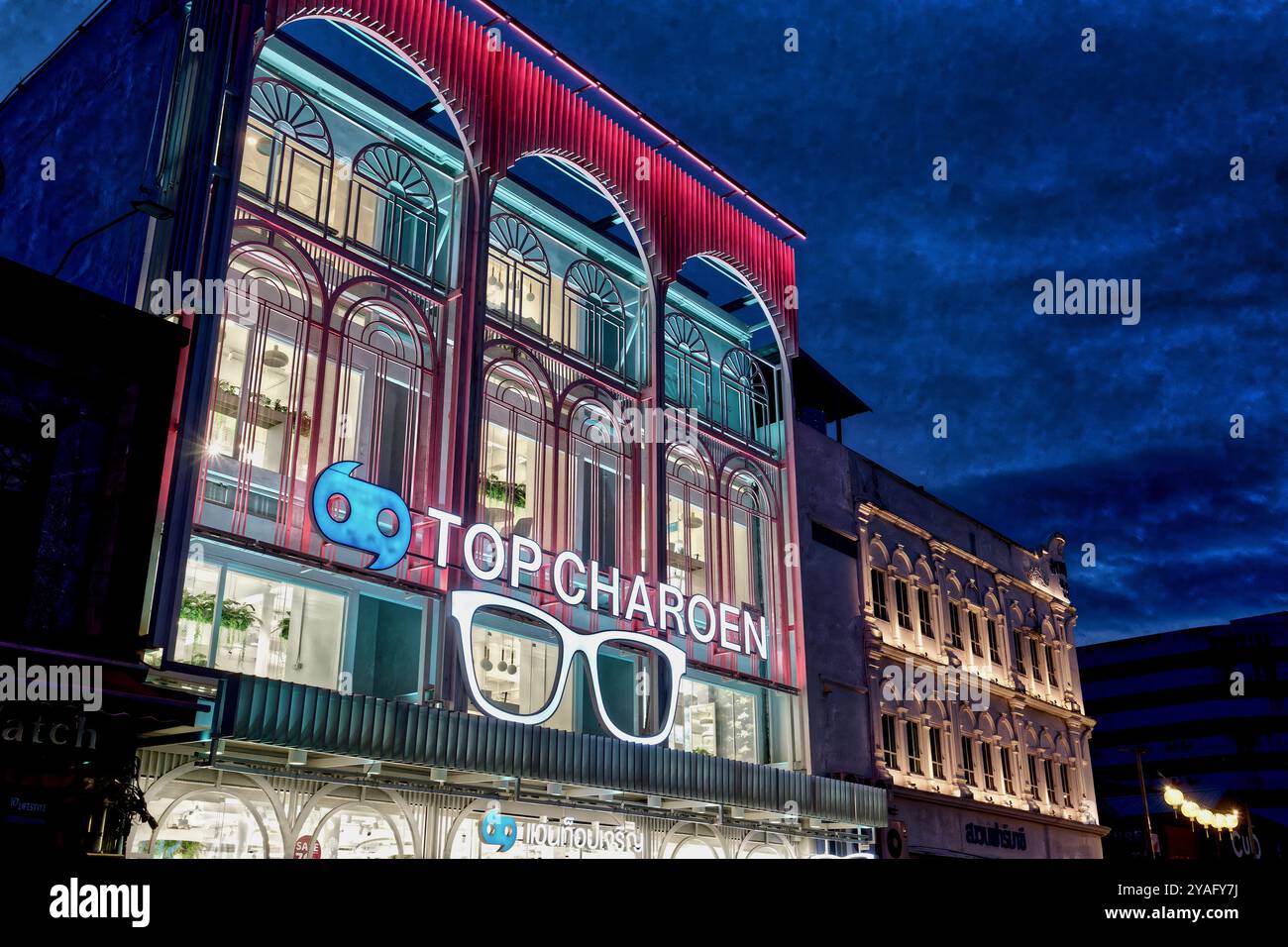 Le crépuscule tombe sur une branche de la chaîne d'opticiens Top Charoen, construit dans le style sino-portugais typique ; dans la vieille ville de Phuket Town, Phuket, Thaïlande Banque D'Images
