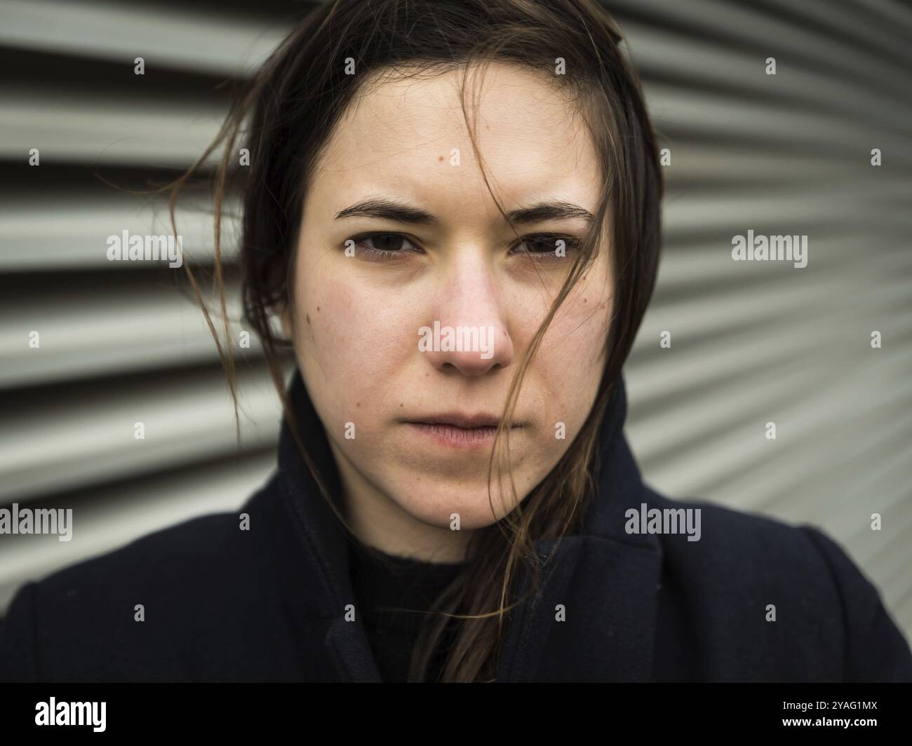 Portrait extérieur d'une femme blanche de 28 ans aux cheveux bruns posant contre un mur industriel, Bruxelles, Belgique, Europe Banque D'Images