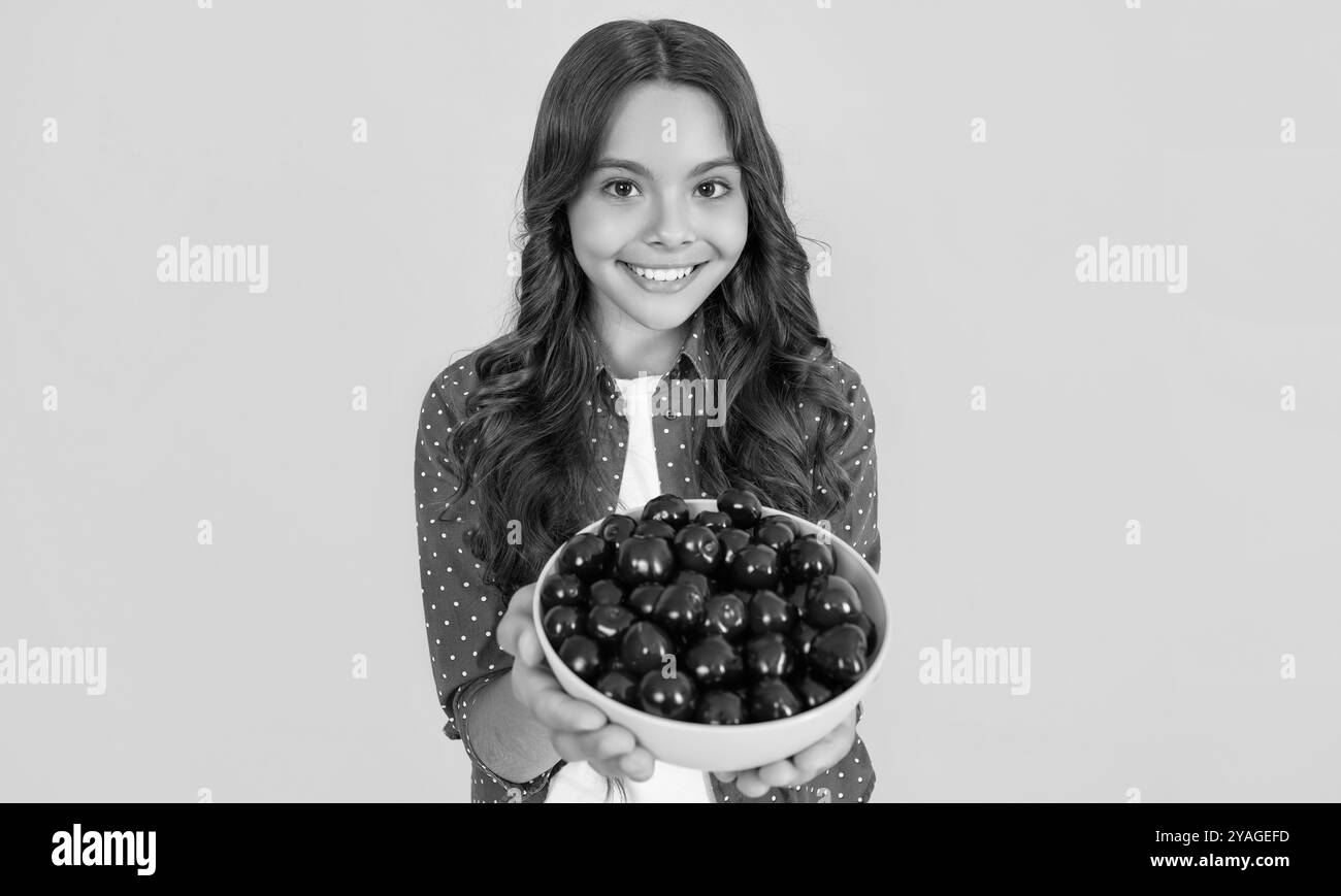 bonne fille de l'adolescence tenir bol de cerise sur fond jaune. foyer sélectif Banque D'Images