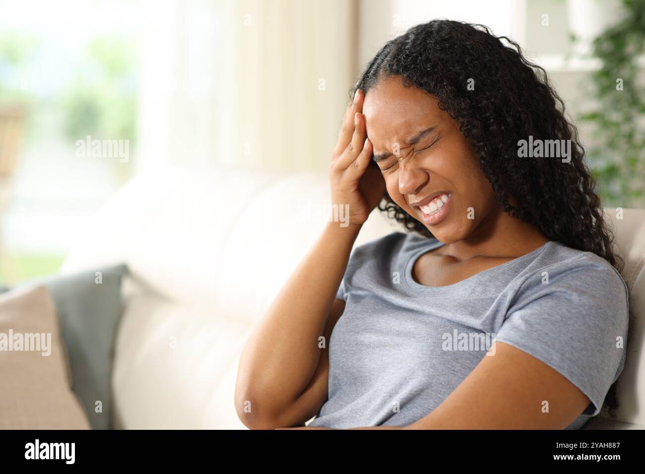 Femme noire souffrant de maux de tête assis sur un canapé à la maison Banque D'Images