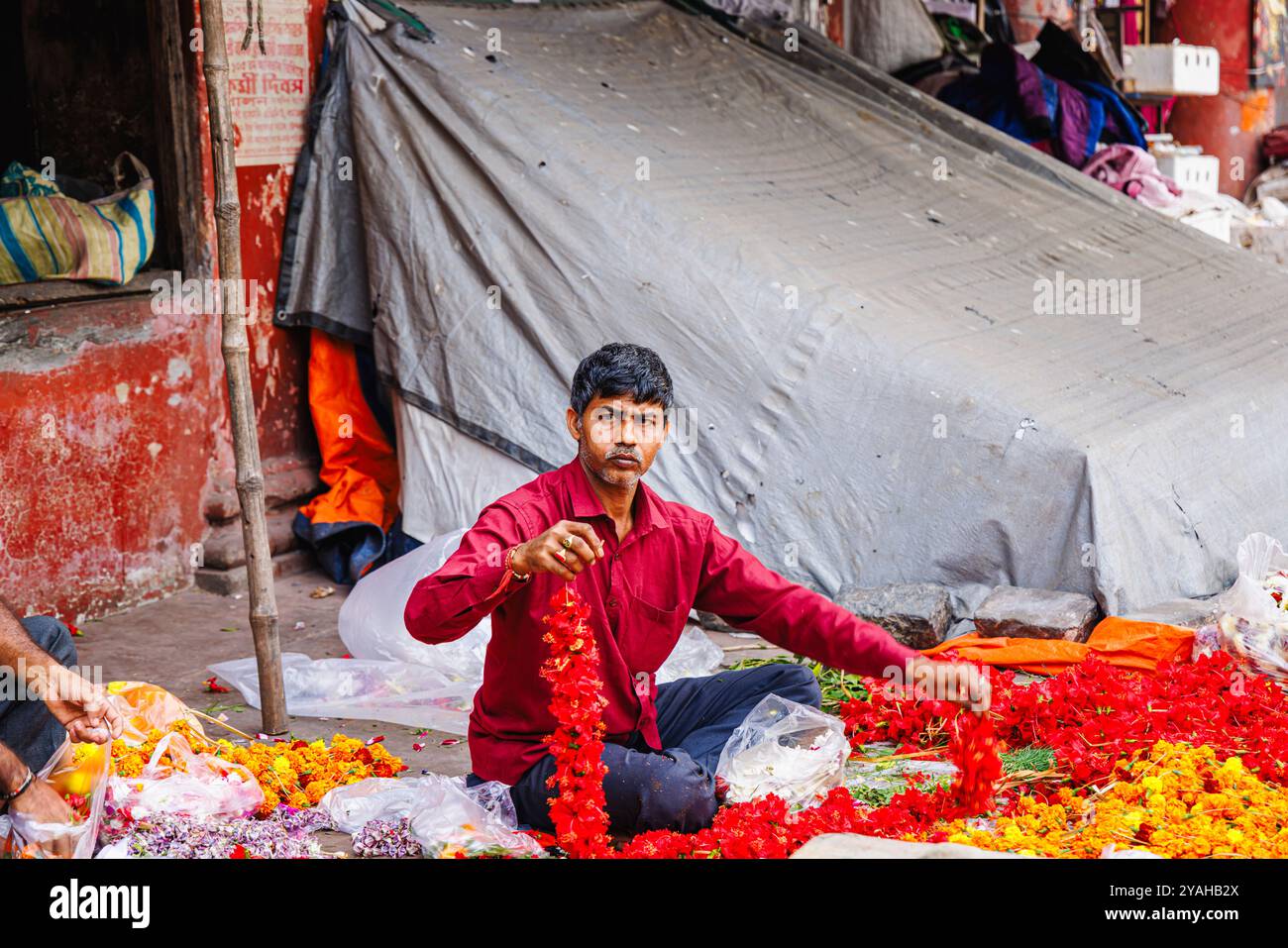 Un vendeur local détient des guirlandes d'hibiscus qu'il fabrique au marché aux fleurs de Howrah à Strand Bank Road, Kolkata (Calcutta), au Bengale occidental, en Inde Banque D'Images