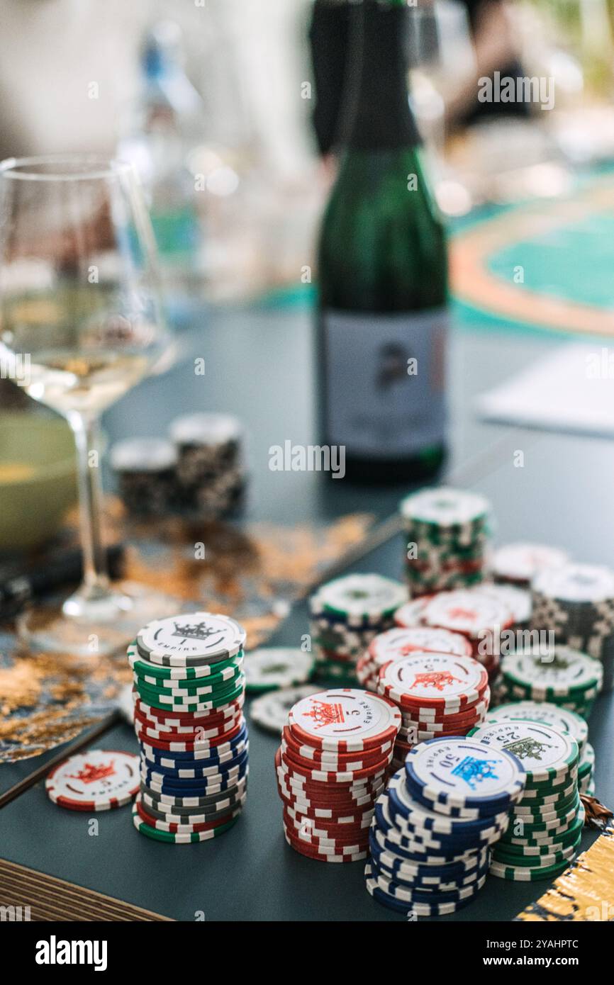 Piles de jetons de casino avec bouteille de vin et verre, jeu de table et concept de dégustation de vin, tendance de divertissement à la maison Banque D'Images