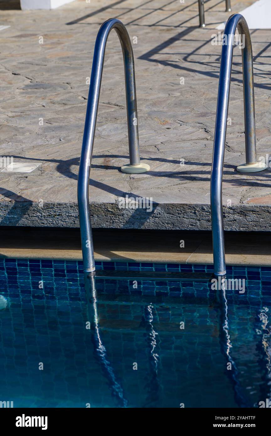 Échelle en acier inoxydable mains courantes (escaliers) dans la piscine avec l'eau bleue et la lumière du soleil (blik of Sun). Vacances, détente, mode de vie sain, conce de sport Banque D'Images