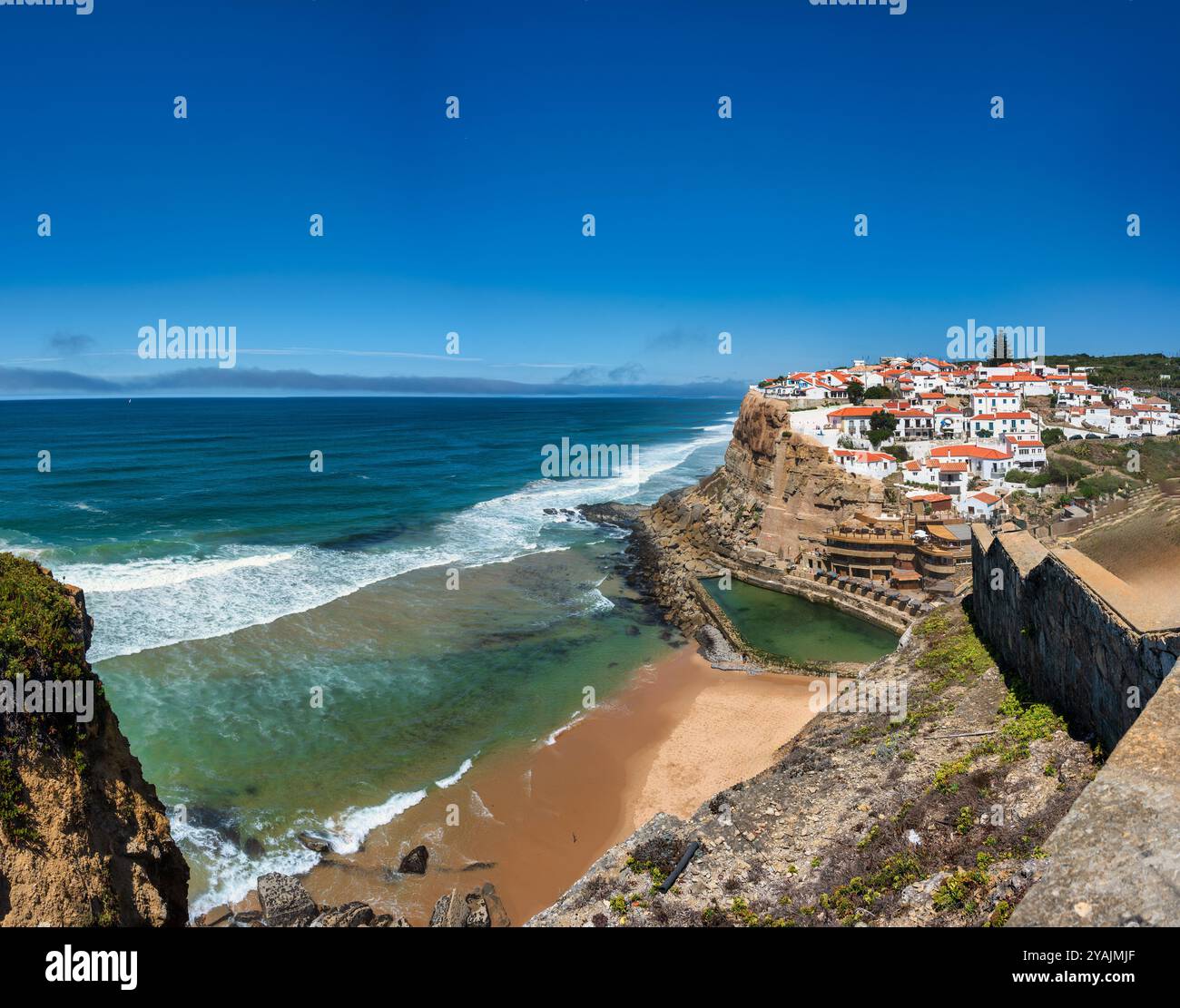 Sintra, Portugal. 24 août 2024. Village côtier sur une falaise surplombant l'océan, avec des vagues qui s'écrasent sur la plage de sable en contrebas, Azenhas do mar à si Banque D'Images