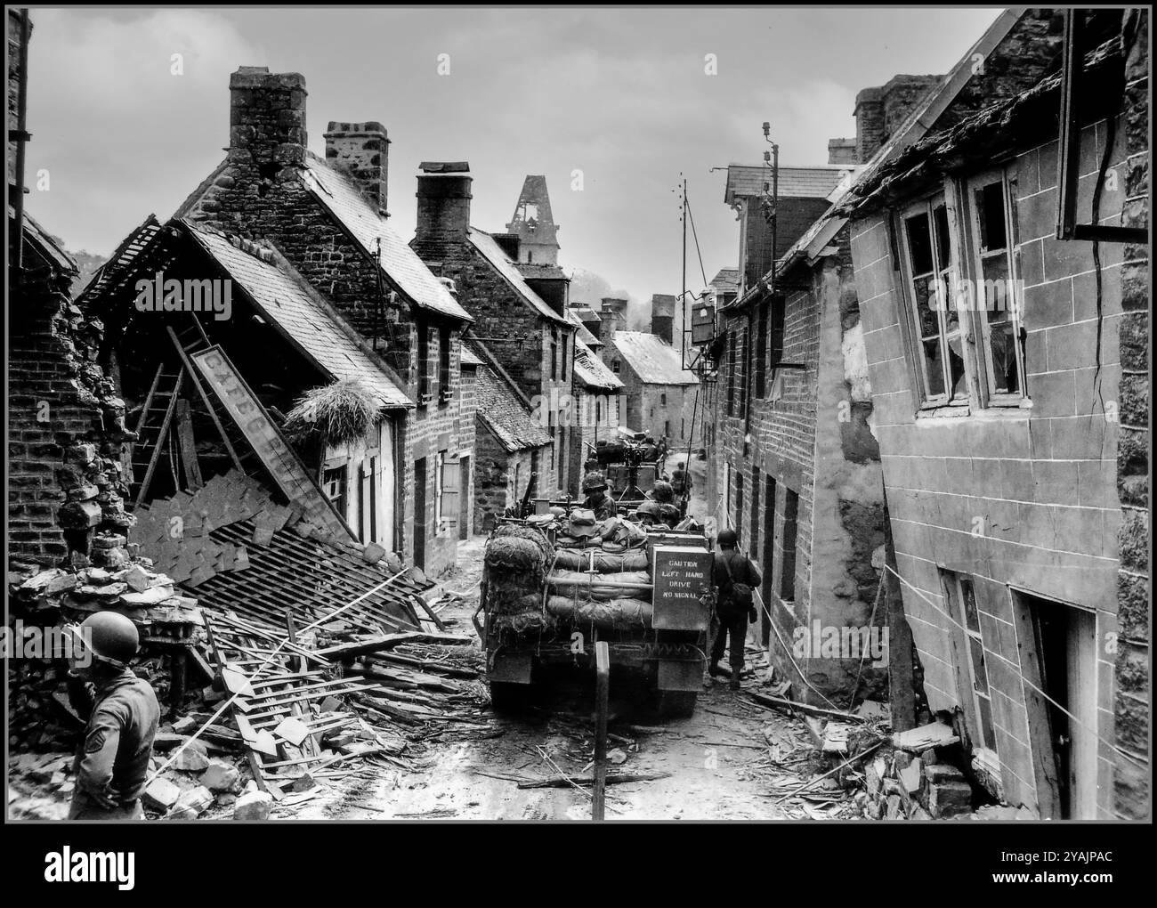 WW2 NORMANDIE les demi-pistes américaines M2 traversent lentement la rue Saint Michel en ruine à Lonlay L'Abbaye, le 14 août 44. Après des batailles féroces avec les forces d'occupation de l'Allemagne nazie après l'assaut initial sur le jour J Normandie France les demi-pistes du combat Command A de la 2ème division blindée américaine se déplacent lentement vers le bas de la rue Saint Michel devant un certain nombre de bâtiments en ruine. Normandie France Banque D'Images