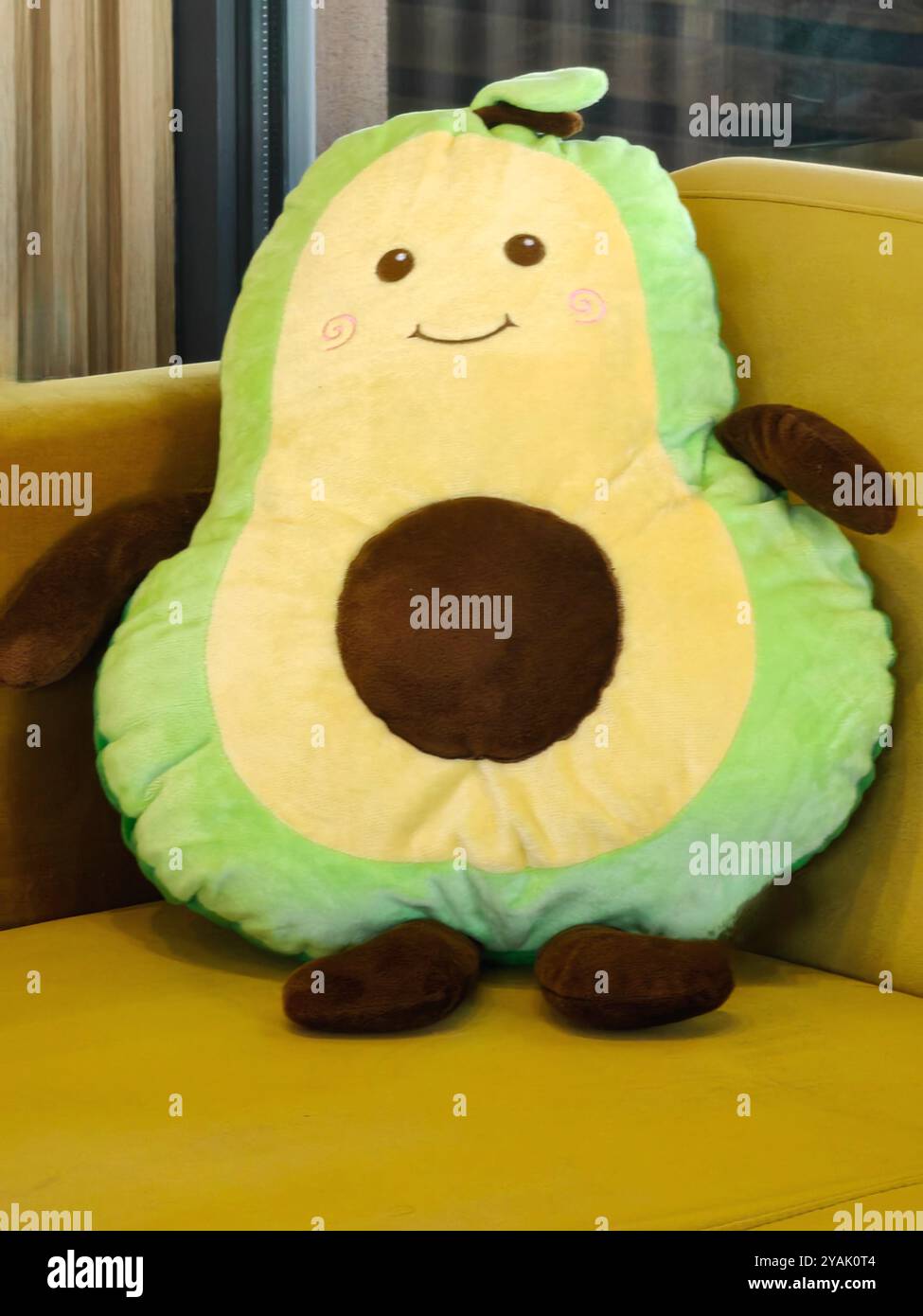 Peluche d'avocat sur canapé vert et jaune - vibrations confortables et vie saine Banque D'Images