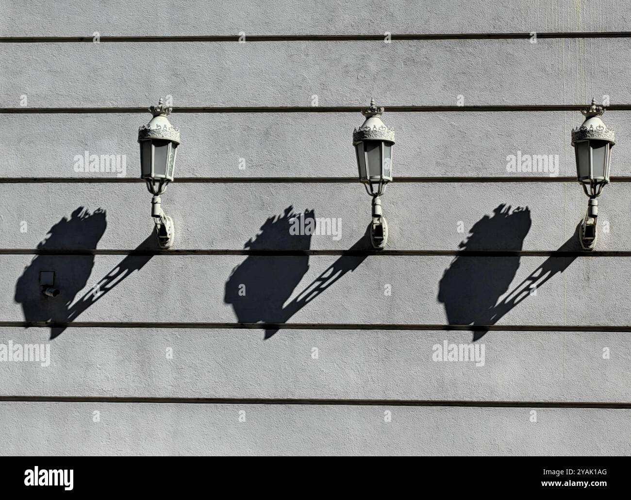 Trois lanternes de style ancien : rythme et motif de lumière et d'ombre sur le mur extérieur Banque D'Images