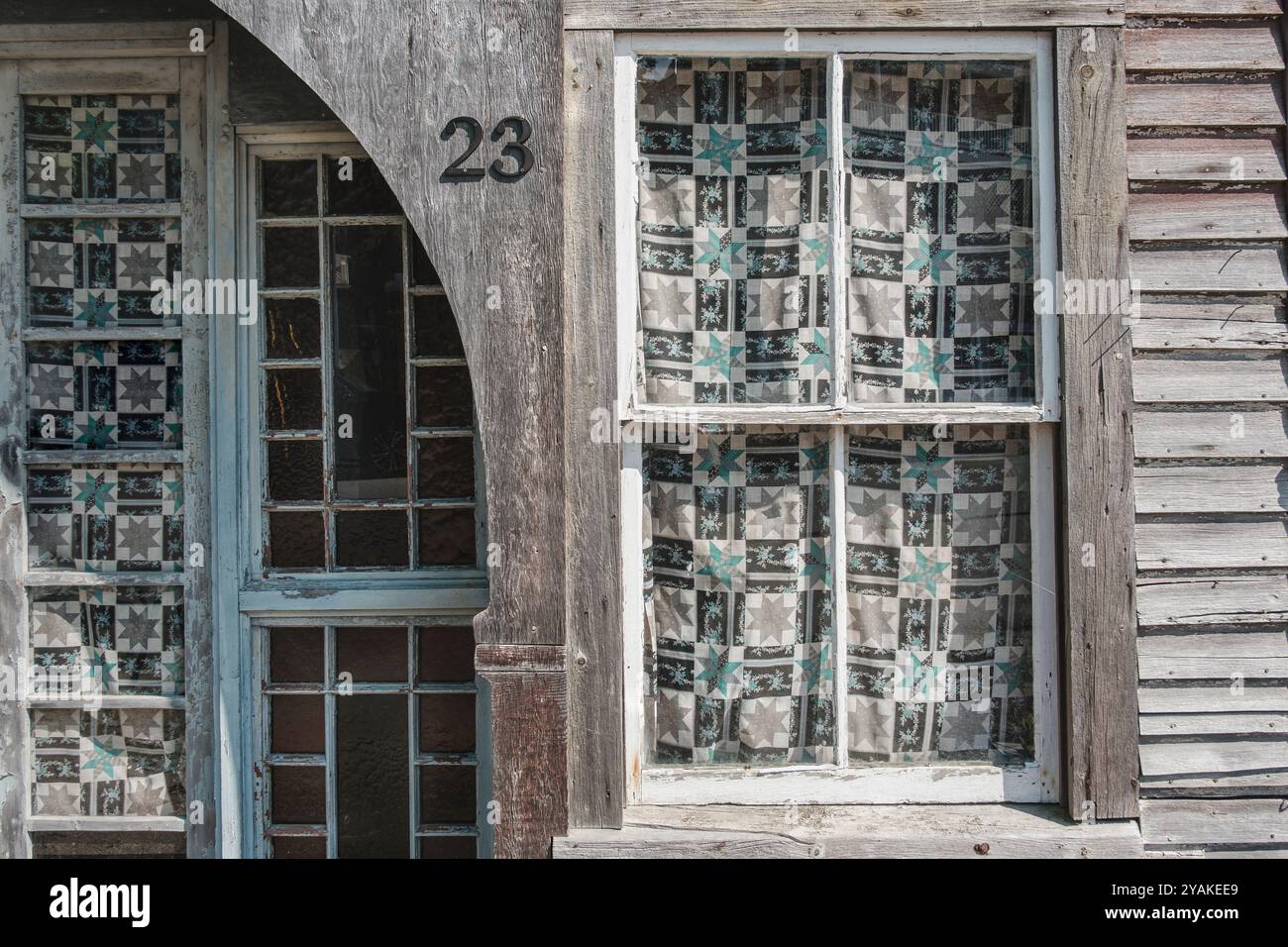 Extérieur de bâtiment altéré avec fenêtres en vitres recouvertes de rideaux à motifs Banque D'Images