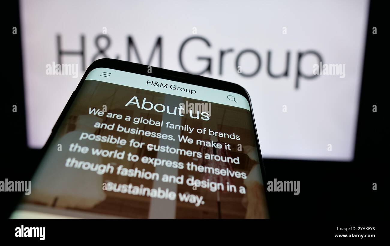 Téléphone portable avec le site de la société de mode suédoise H M Hennes Mauritz AB sur l'écran devant le logo. Concentrez-vous sur le coin supérieur gauche de l'écran du téléphone. Banque D'Images