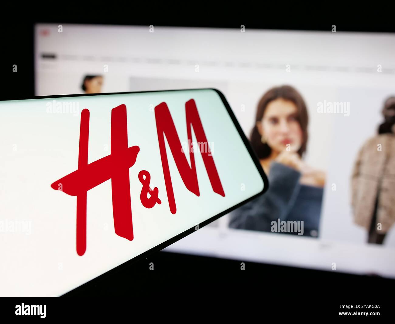 Smartphone avec logo de la société de mode suédoise H et M (HM) sur l'écran en face du site Web de l'entreprise. Mettez l'accent sur le centre-gauche de l'écran du téléphone. Banque D'Images