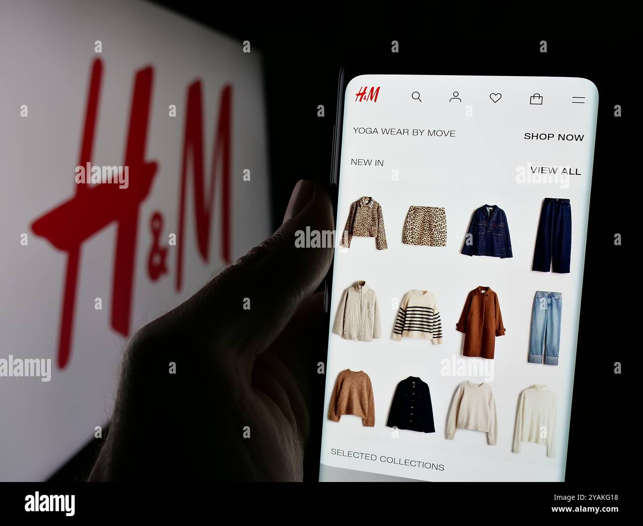 Personne tenant le téléphone portable avec la page Web de la société de mode suédoise H et M (HM) sur l'écran devant le logo. Concentrez-vous sur le centre de l'écran du téléphone. Banque D'Images