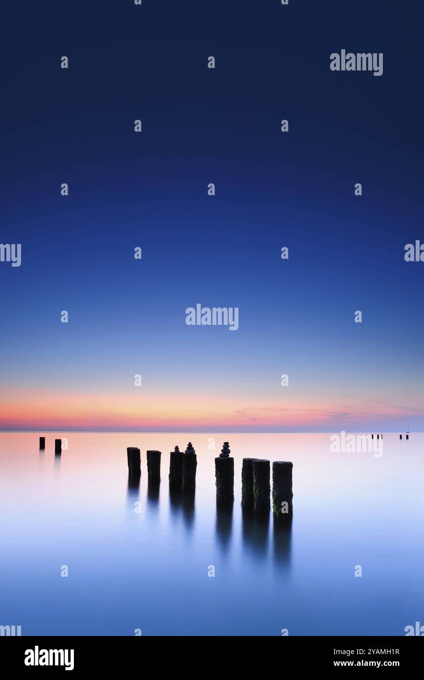Pyramides de pierre sur les vieux groynes avec des algues dans l'eau sur la plage de la mer Baltique, longue exposition au coucher du soleil, Wustrow, Fischland-Darss-Zingst peninsu Banque D'Images