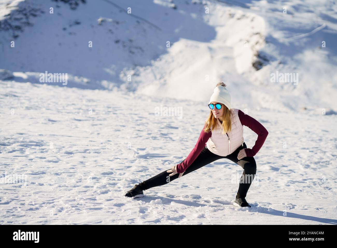 Femme élégante faisant de l'exercice de yoga sur un terrain enneigé Banque D'Images
