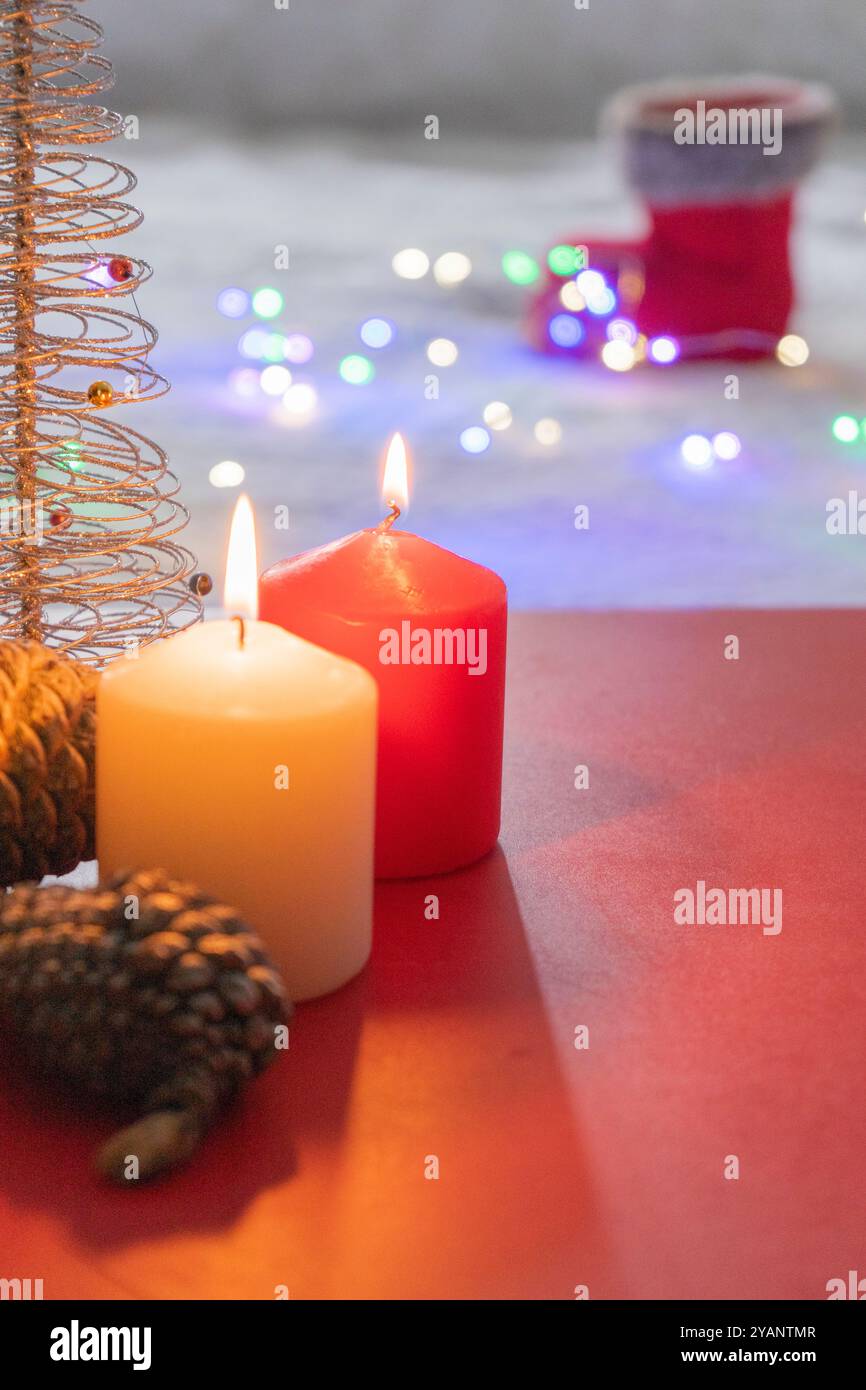 Fond de Noël et du nouvel an avec bougies allumées, pommes de pin et lumières de Noël Banque D'Images