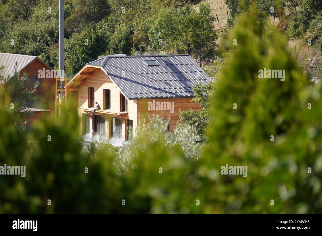 Une maison moderne en bois nichée dans la nature, capturant la beauté d'un environnement paisible et la simplicité de la vie à la campagne. Banque D'Images