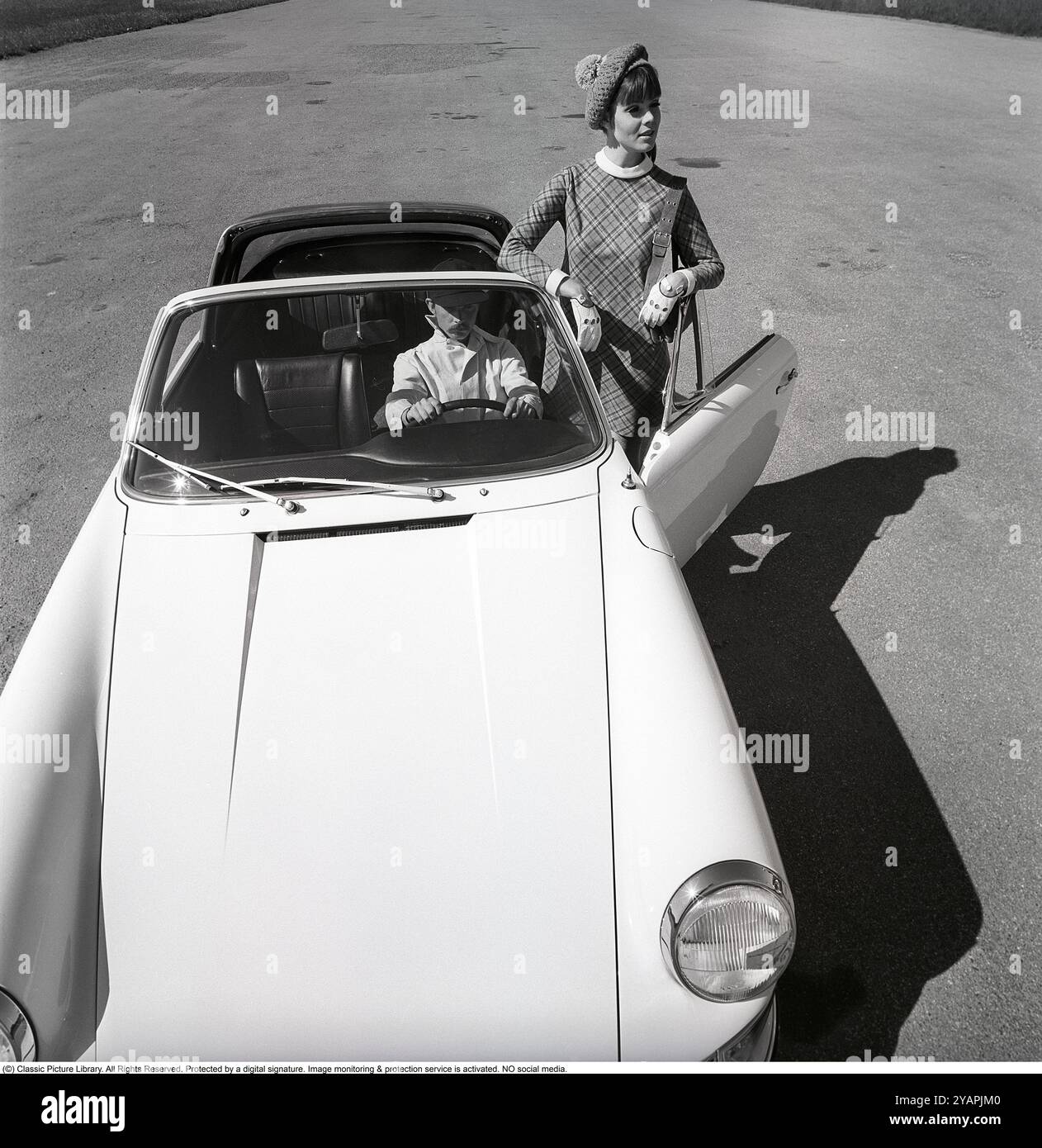 Porsche juin 1967. Un modèle de mode habillé à la mode de l'année chez un modèle Porsche 911 Targa Soft Window. Un cabriolet avec une lunette arrière en vinyle dans le capot, d'où le surnom Soft Window. Dans le siège du pilote professionnel Sten Axelsson qui pilotait Porsche à cette époque. Photo prise avec Hasselblad Banque D'Images