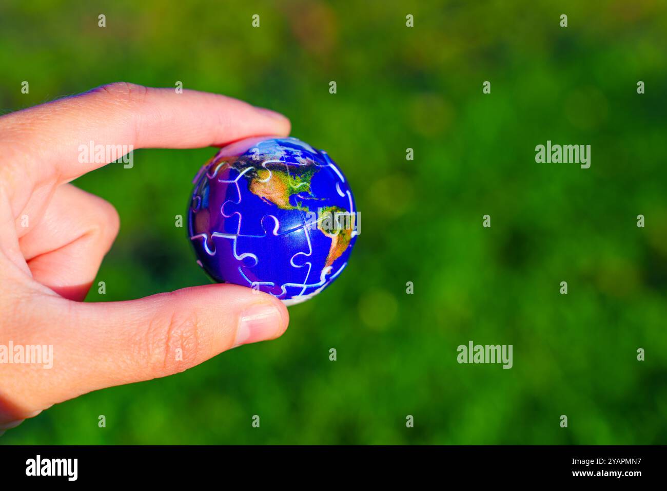 Main tenant un globe de puzzle miniature 3D, symbolisant la responsabilité personnelle envers la durabilité environnementale. Banque D'Images