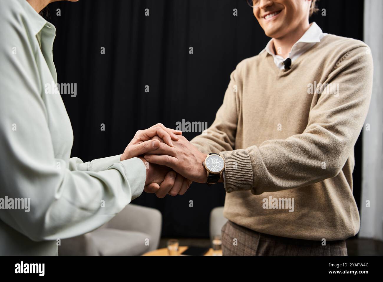 Un journaliste serre chaleureusement la main d’un spécialiste lors d’un dialogue perspicace dans un studio moderne. Banque D'Images