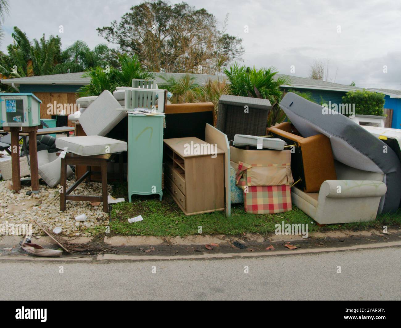 Gros tas de déchets, meubles, articles ménagers empilés sur le côté d'une bordure de rue en briques. Après une tempête endommageant l'inondation d'une onde de tempête d'eau. Banque D'Images