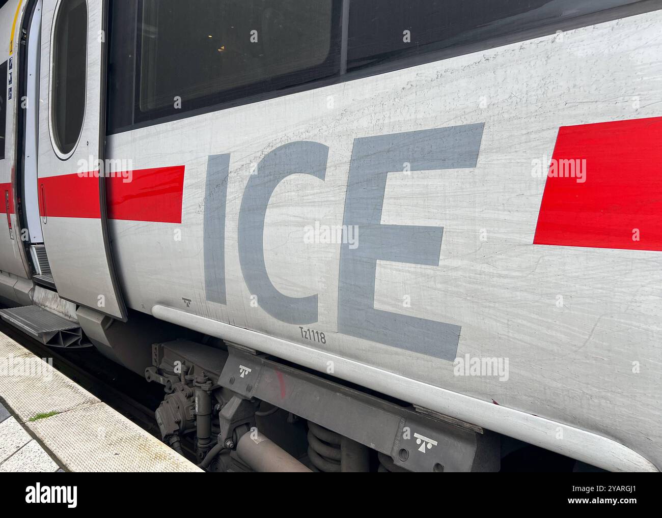 Symbolbild Nahaufnahme eines ICE-Zuges, Großer ICE -Schriftzug auf der Seite, markante rote Linie, geöffnete Tür am Bahnsteig, technisches Detail des Fahrwerks sichtbar, Symbol für Hochgeschwindigkeitsverkehr der Deutschen Bahn, moderner und effizienter Zug, wichtige Rolle Präsenz im Fernverkehr öffentlichen symbole pour vitesse élevée t Banque D'Images