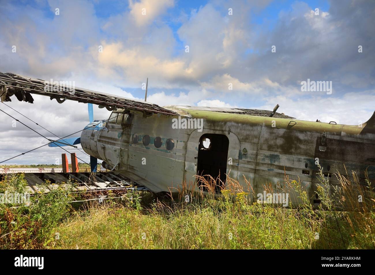 Ancien avion écrasé et abandonné debout dans le champ contre un ciel bleu nuageux. Petit avion à hélice au cimetière de l'avion Banque D'Images