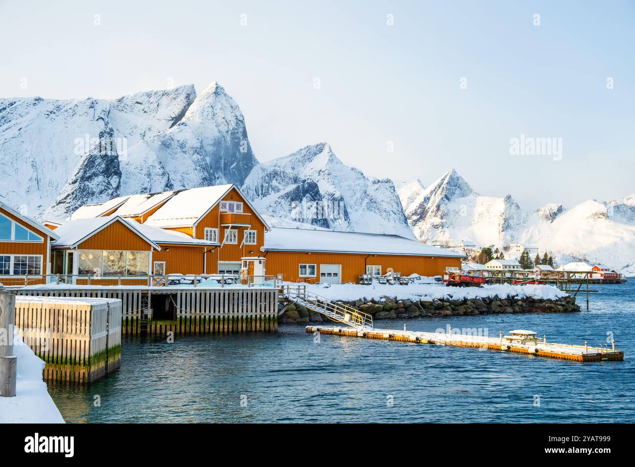 Sakrisoy village de pêcheurs et montagnes enneigées en hiver sur les îles Lofoten, Norvège. Paysage d'hiver avec des maisons traditionnelles de rorbu jaune sur pilotis Banque D'Images