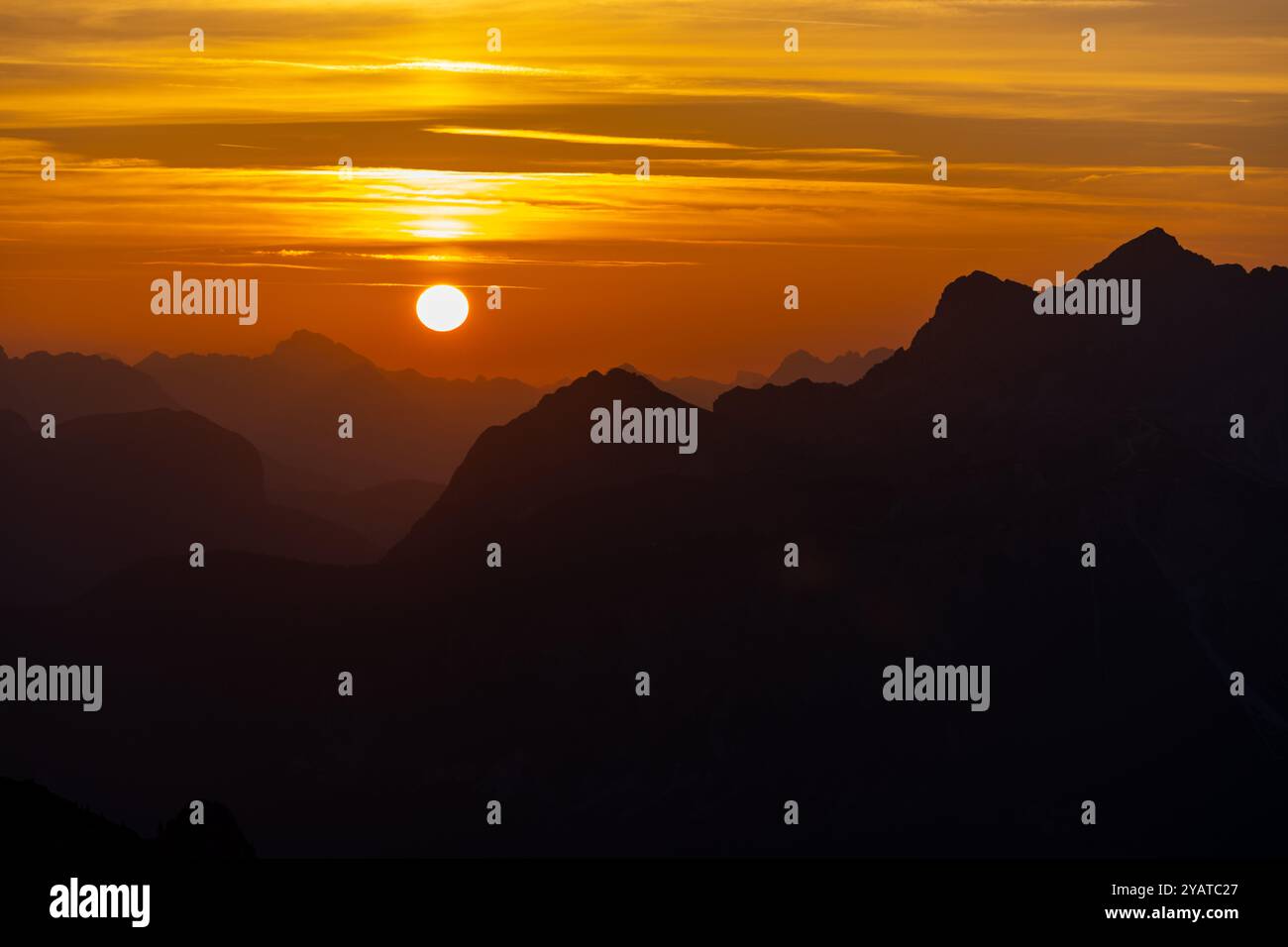 Ciel de coucher de soleil dans les montagnes. Dolomiti Alpes gamme à la lumière du coucher du soleil, le ciel brûlant sang rouge coucher de soleil avec des sommets de montagne silhouettes et des nuages mystérieux Banque D'Images