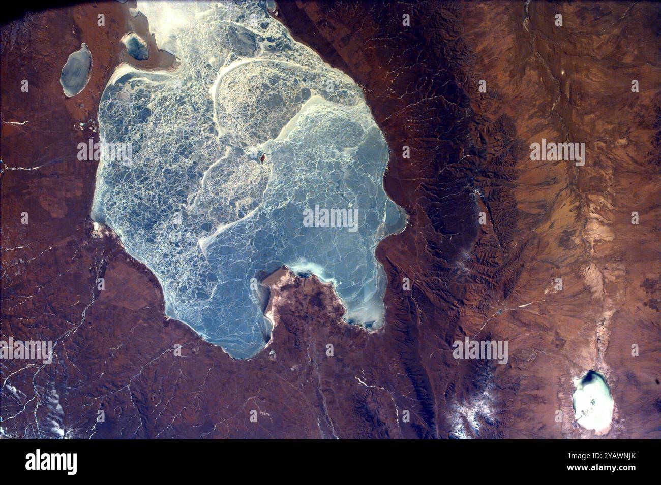 Cette image capture presque tout le Quinghai, le plus grand lac de Chine. Ce lac a une altitude de surface de 10 450 pieds ; remplissant partiellement l'un des bassins versants les plus fermés à l'est de l'Asie centrale. Il est situé dans la province du Quinghai sur le plateau tibétain du Quinghai. De petites villes de marché, dont Tianjun et Ganga, parsèment la périphérie du lac Quinghai. C'est ici, dans l'une des régions les plus ethniquement diversifiées de Chine, que les nomades tibétains encaissent leur bétail. Banque D'Images