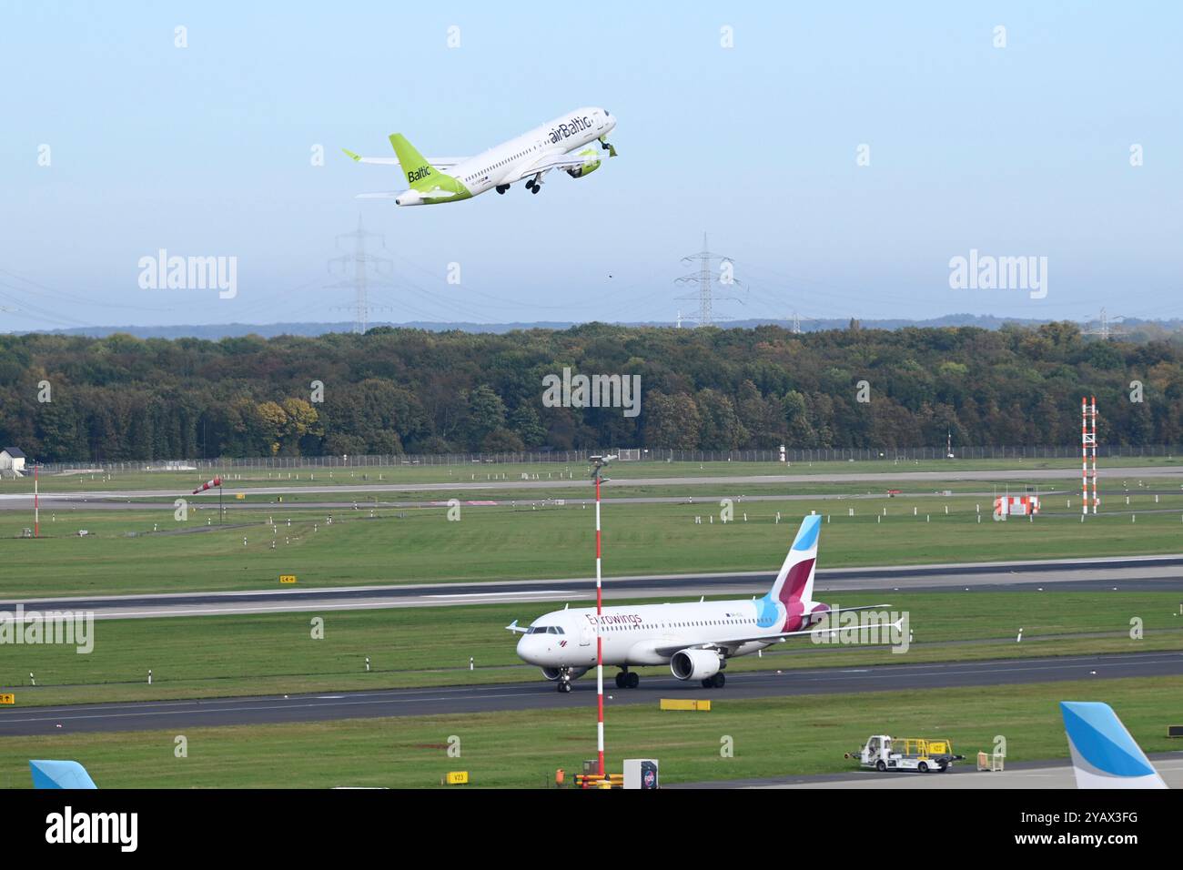 Duesseldorf, Deutschland. 15 octobre 2024. Un Airbus 220 d'Air Baltic décollant, devant un Airbus atterri d'Eurowings roule vers le terminal de l'aéroport de Duesseldorf, le 15 octobre 2024. Crédit : dpa/Alamy Live News Banque D'Images