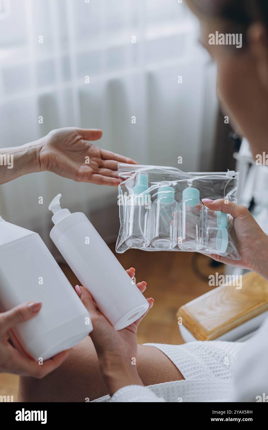 Cosmétologue montre au client un produit cosmétique et des bouteilles en plastique de voyage, maquette de bouteille de crème. Photo de haute qualité Banque D'Images