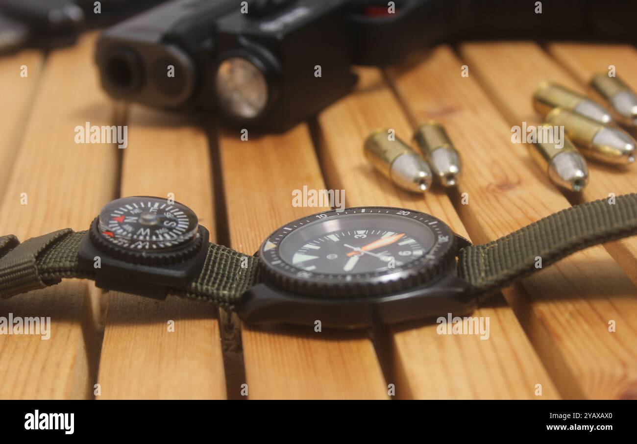 Montre militaire avec boussole et pistolet sur la table en bois Banque D'Images