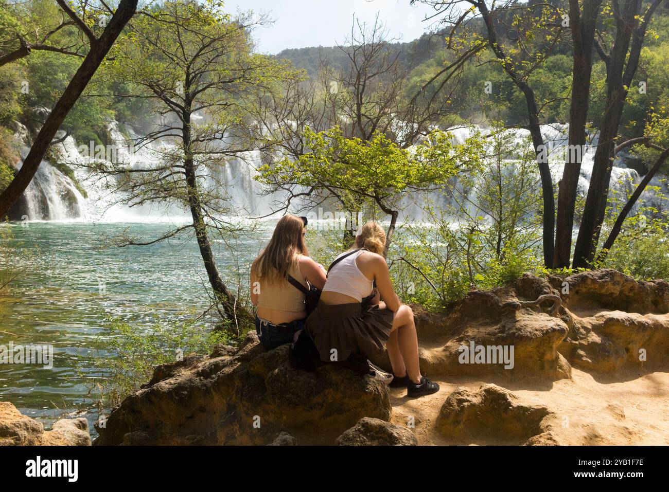 Deux jeunes femmes visiteuses apprécient la vue depuis un point de vue sur la rivière Kirka qui coule sur la cascade de roche / cascades / chute d'eau. Parc national de Krka. Croatie. (138) Banque D'Images