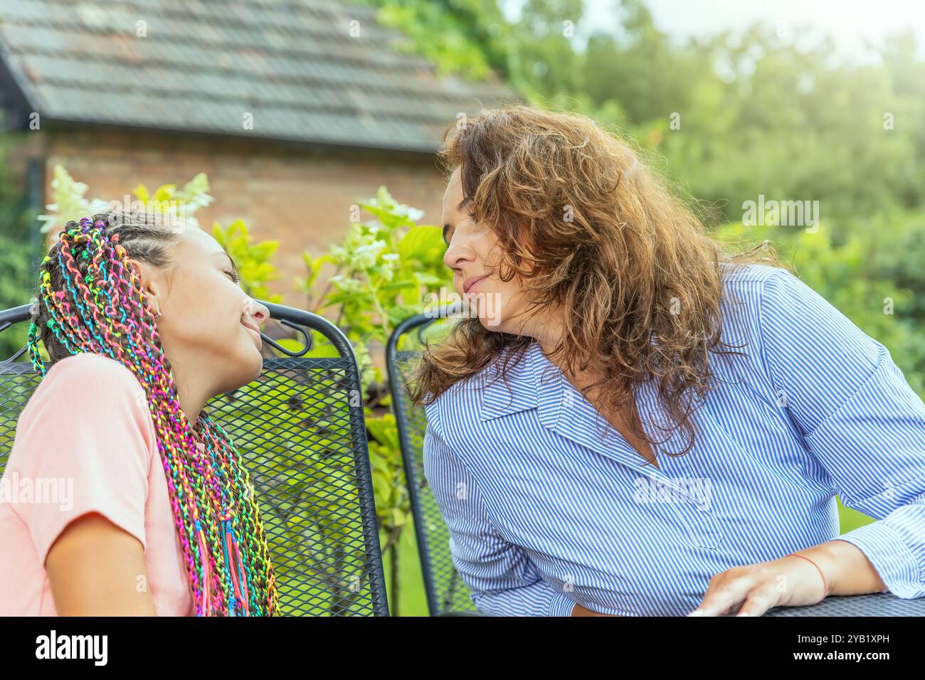 Portrait de mère et fille se regardant assis à la table de jardin. Horizontalement. Banque D'Images