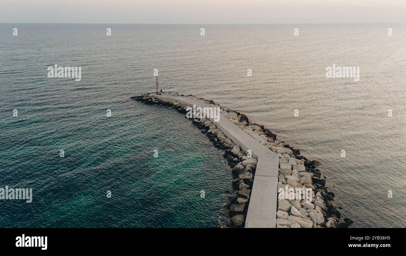 Vue aérienne d'une jetée s'étendant dans la mer Adriatique tranquille à Mola di Bari au lever du soleil, offrant une scène sereine et pittoresque. Idéal pour Concep Banque D'Images
