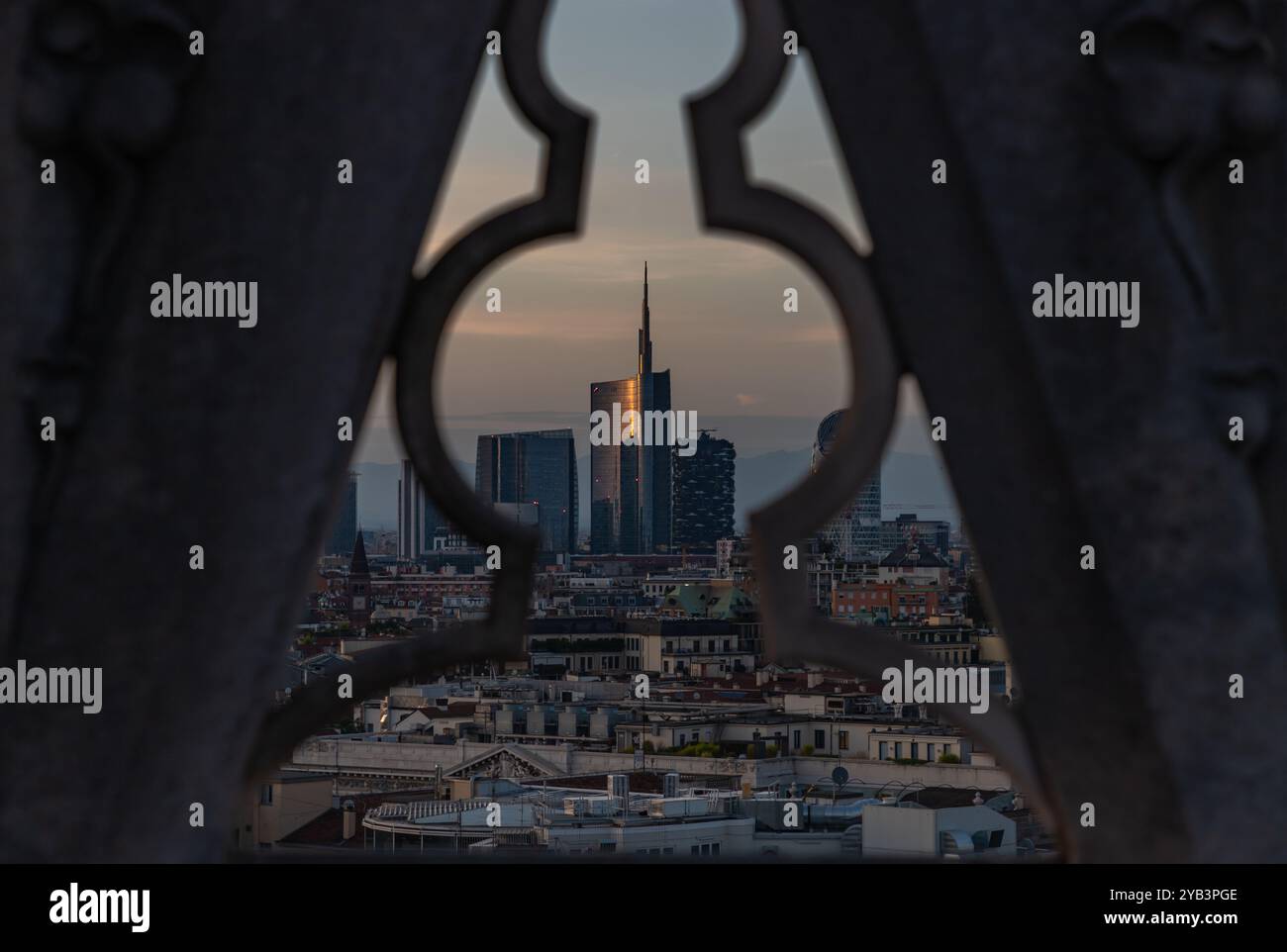 Une photo du Duomo di Milano ou du toit de la cathédrale de Milan surplombant le quartier des affaires de Porta Nuova, en particulier la Tour Unicredit, au coucher du soleil. Banque D'Images