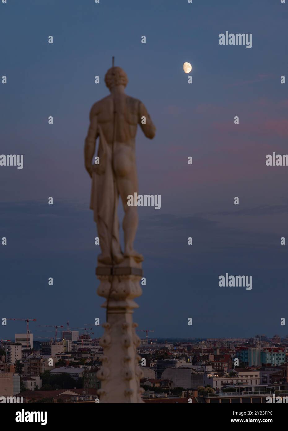Une photo d'un Duomo di Milano ou statue de la cathédrale de Milan surplombant la lune au coucher du soleil. Banque D'Images