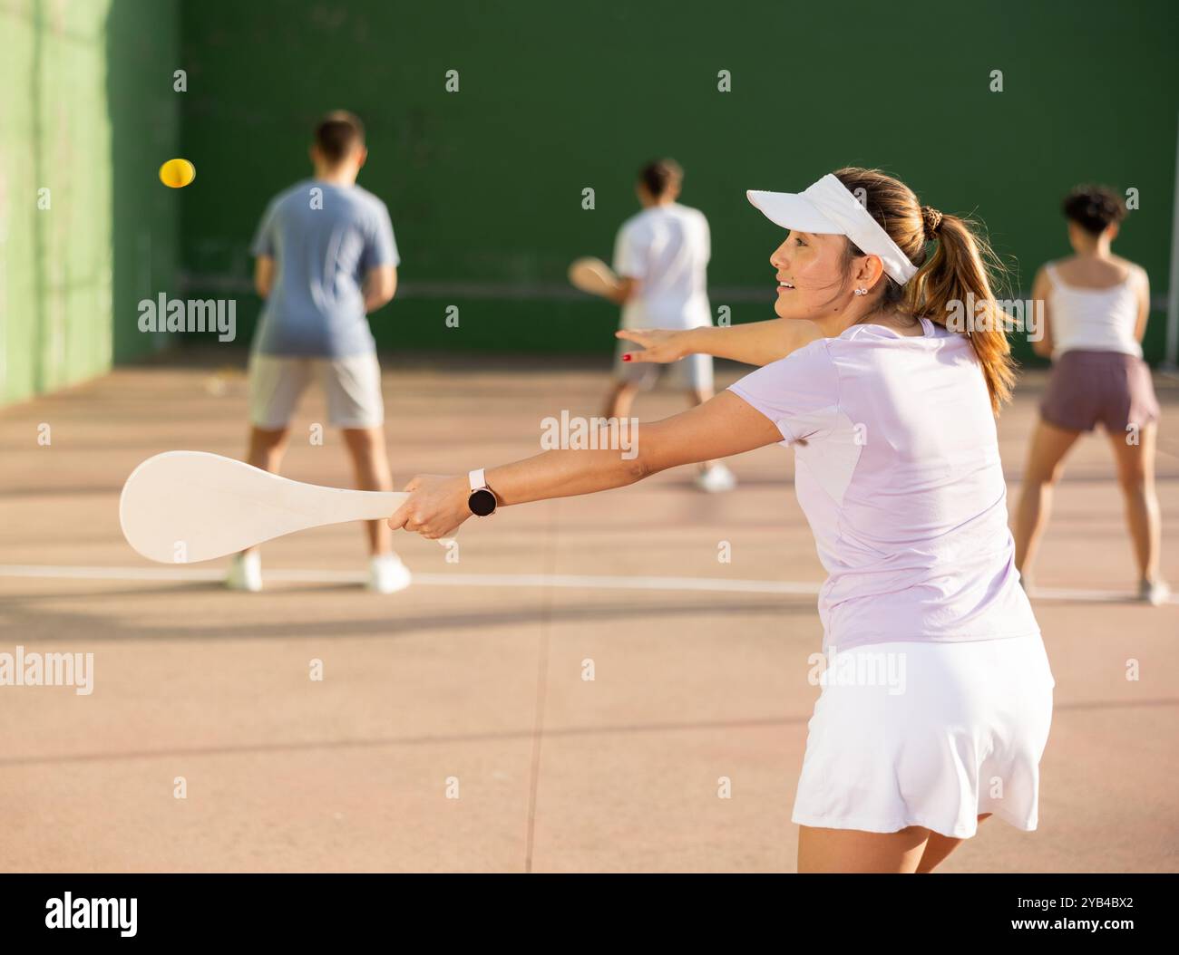 Femme servant le ballon pendant le jeu frontenis à l'extérieur Banque D'Images