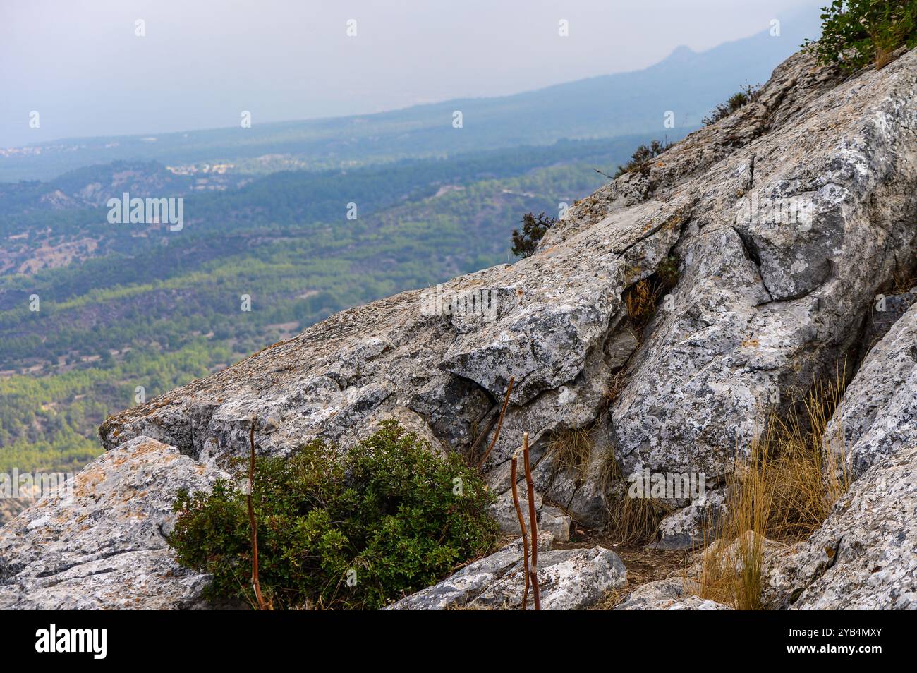 Les aventuriers parcourent des chemins rocheux sur un sommet de montagne, entourés de vastes vallées verdoyantes et de collines lointaines sous un ciel nuageux, embrassant le beau de la nature Banque D'Images