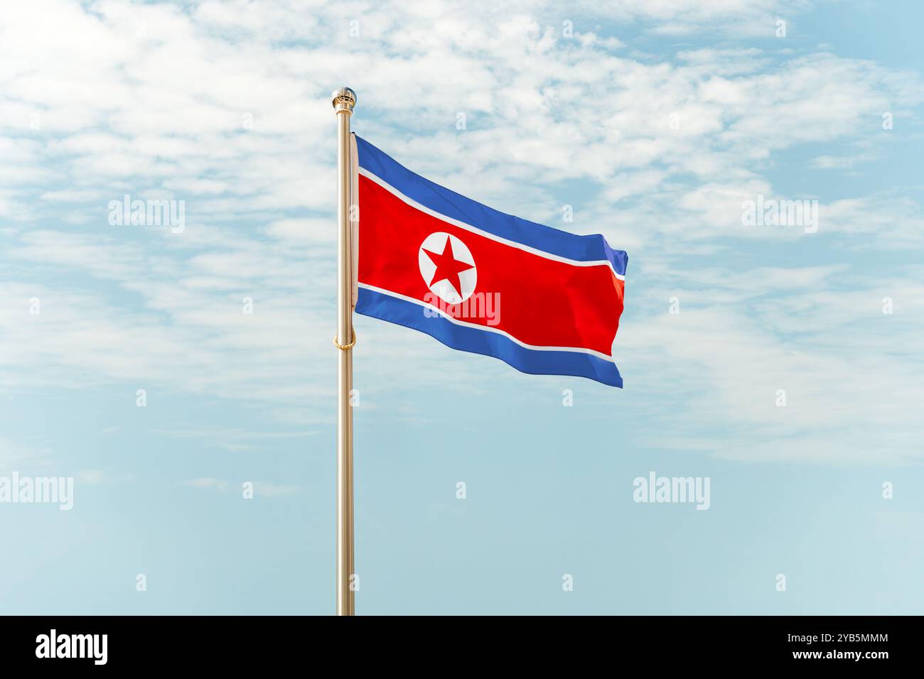 Le drapeau de la Corée du Nord, fond d'un ciel nuageux bleu Banque D'Images